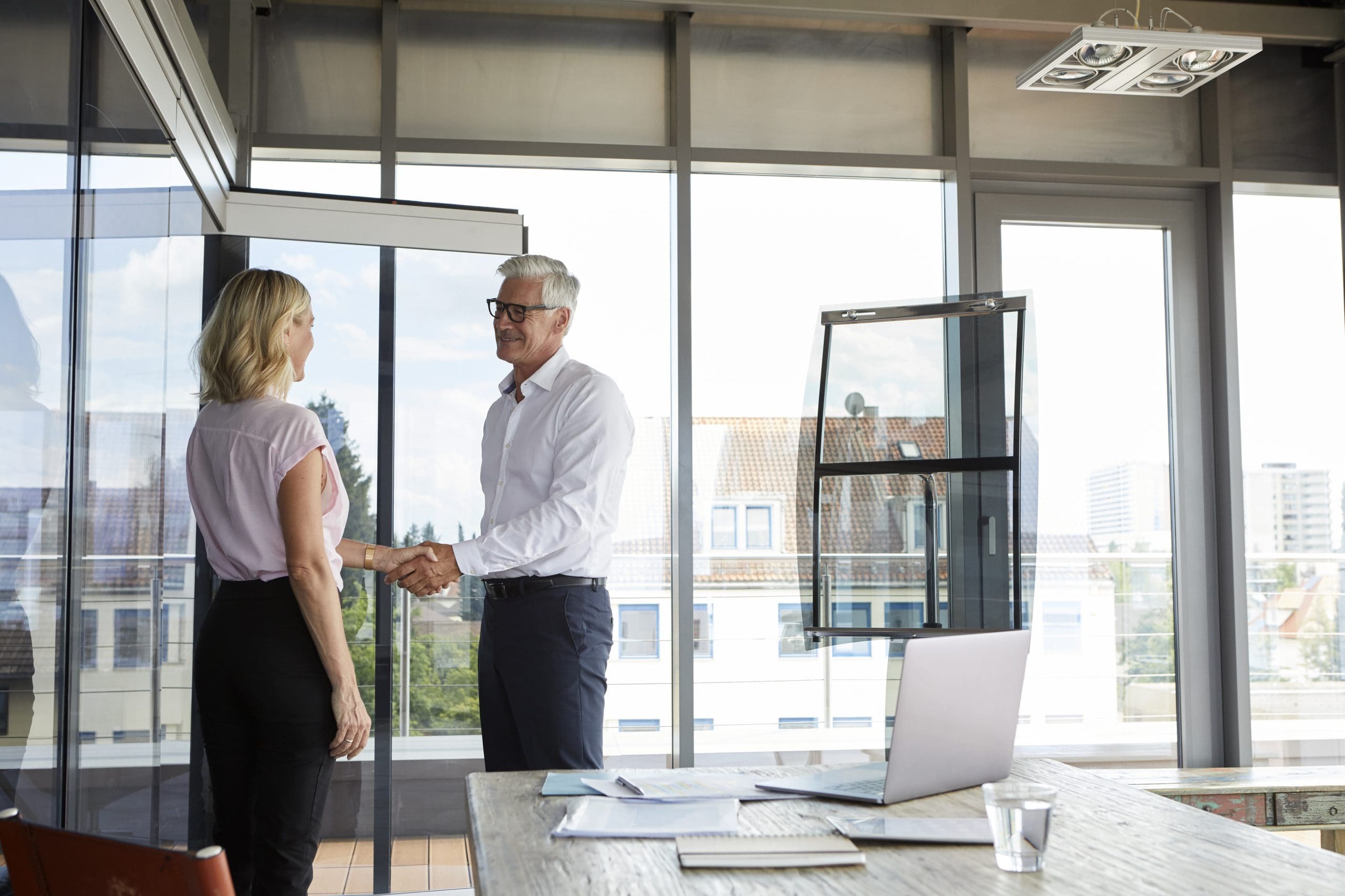 Businessman and woman shaking hands in office